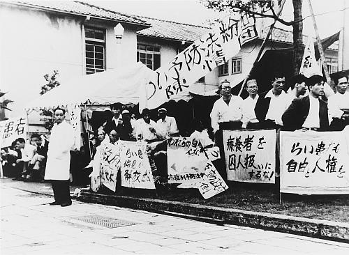Manifestation de la Fédération nationale des patients de la lèpre en 1953, derrière le bâtiment abritant la Chambre des conseillers. Crédit~: Musée national de la maladie de Hansen 国立ハンセン病資料館